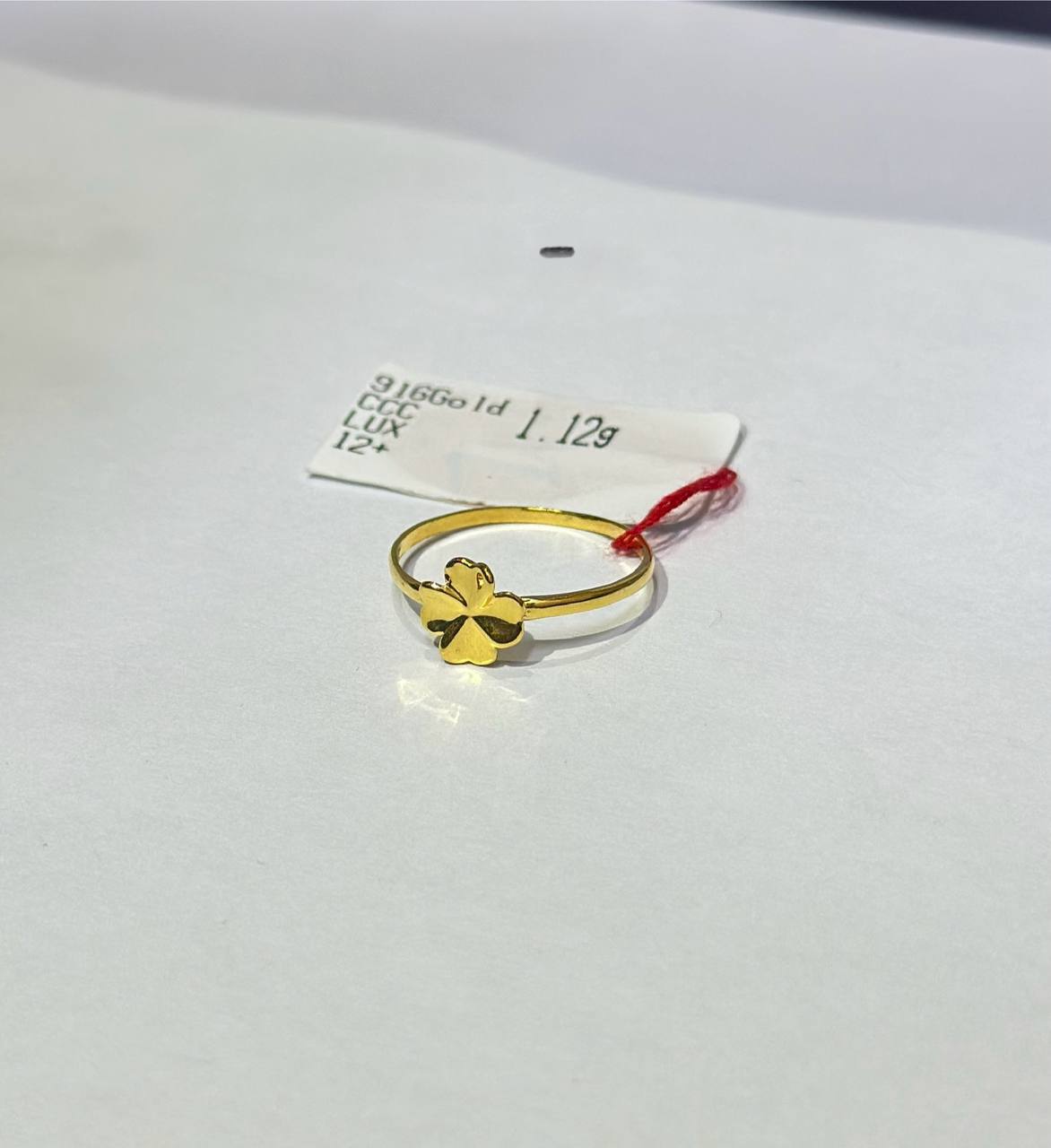 "Gold ring with a four-leaf clover design on a white background"