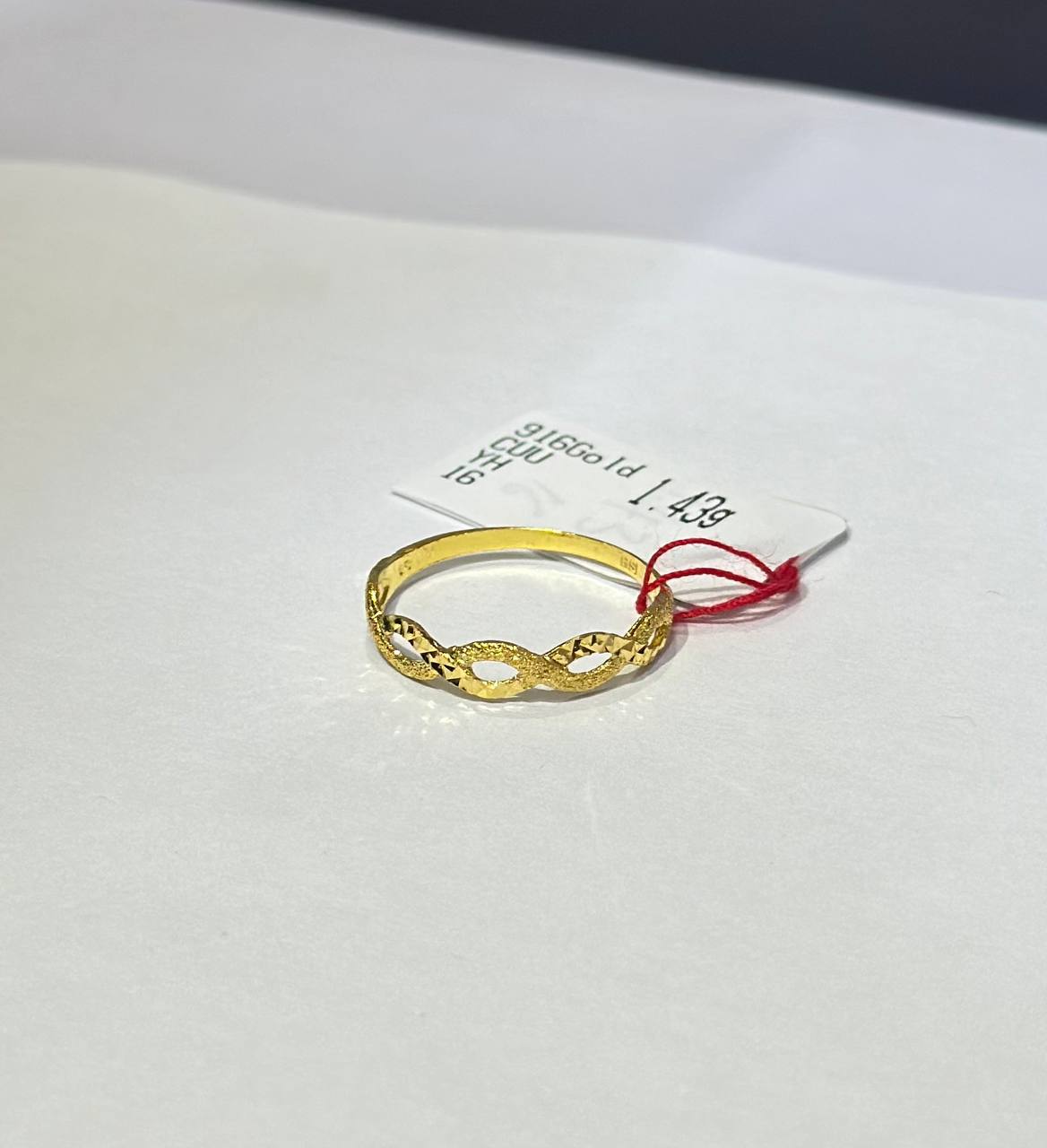 "Gold ring on a white card with text"