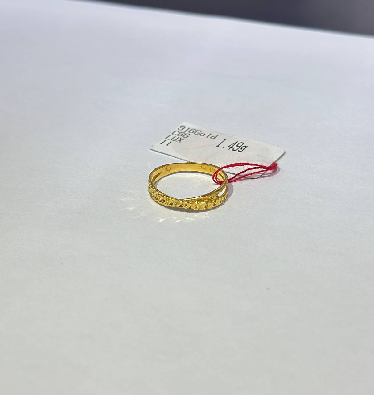 "Gold ring on a white surface with a price tag attached"